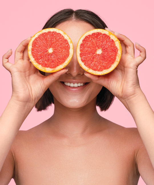 Lady smiling holding two grapefruits over eyes