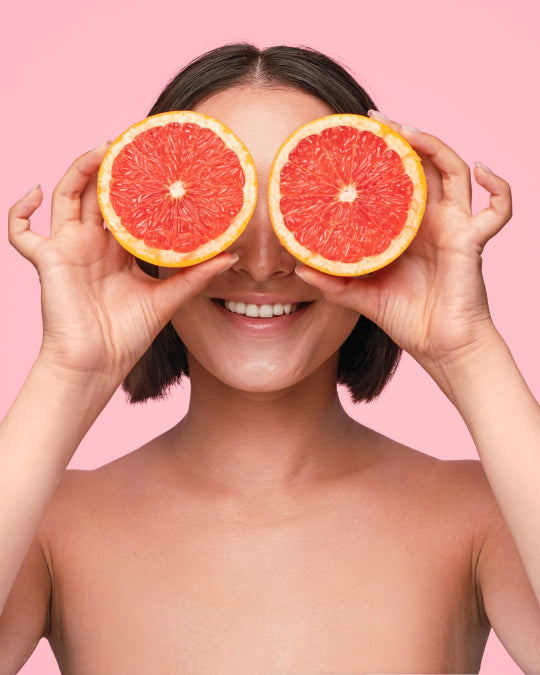 Lady smiling holding two grapefruits over eyes